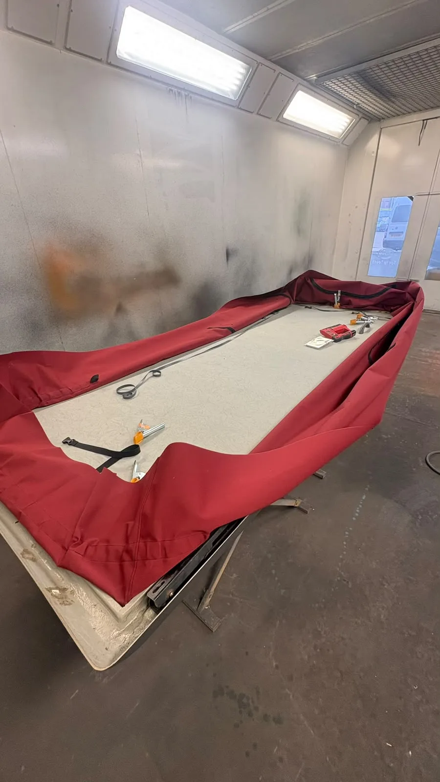 Red pop-top canvas and roof assembly laid out for work in the JCC workshop