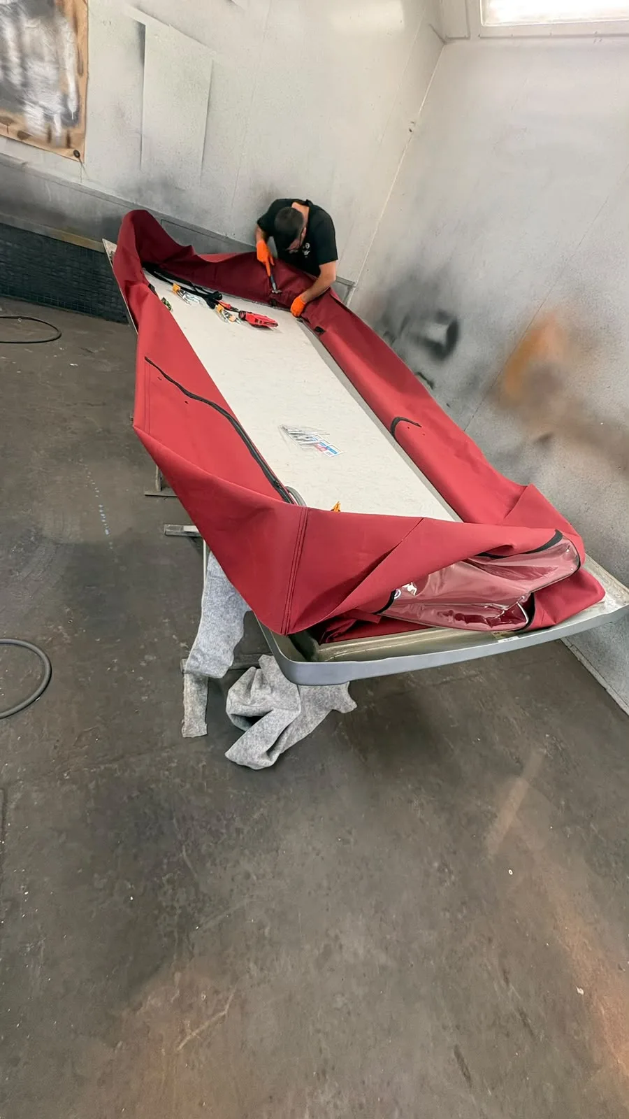 Detached roof and red pop-top fabric viewed from the end of the work stand
